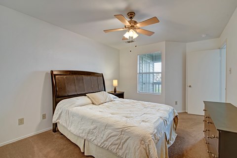 A bedroom with a large bed and a ceiling fan.
