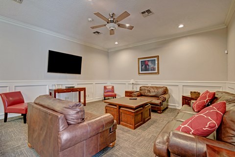 A living room with a brown leather couch and a flat screen TV mounted on the wall.