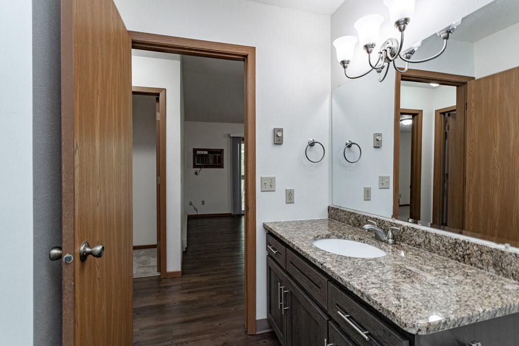 a bathroom with a sink and a mirror and a door to a hallway