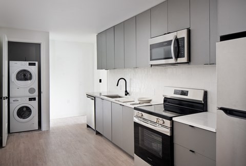 a kitchen with white cabinets and appliances and a washer and dryer in it
