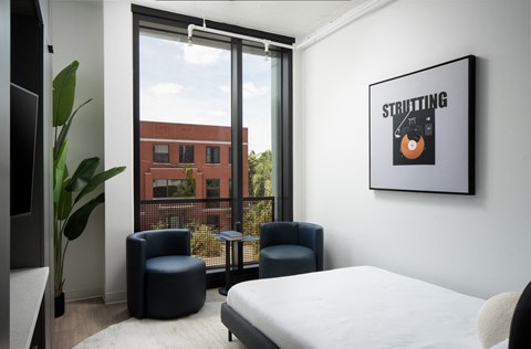 a bedroom with a bed and two chairs and a window