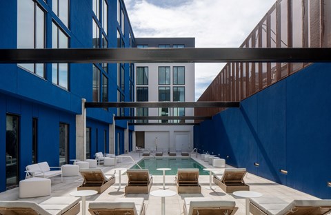 the pool area of a blue building with chairs and a pool