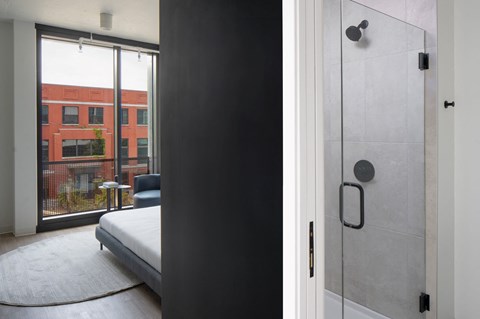 A modern bedroom with a large bed and a glass door leading to a balcony.