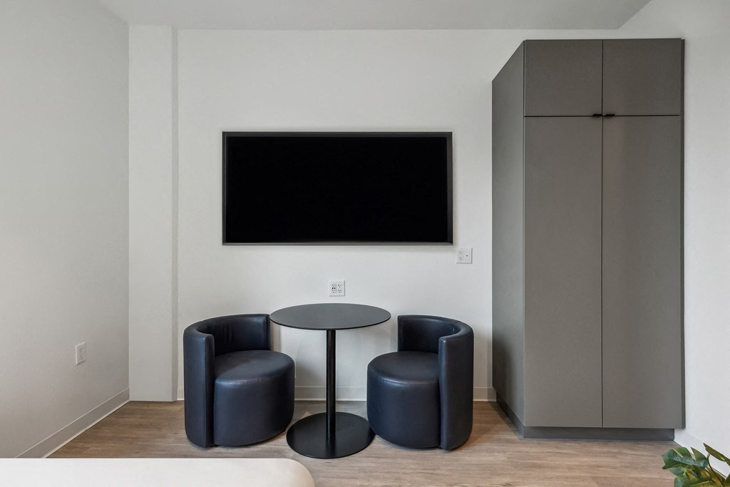 a room with a table and two chairs and a television on the wall