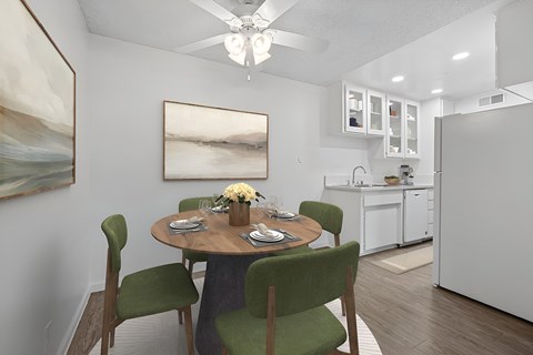 Kitchen 1005 Via Zapata apartment home with wood-style plank flooring, white cabinetry, white appliances and dining nook with overhead ceiling fan.