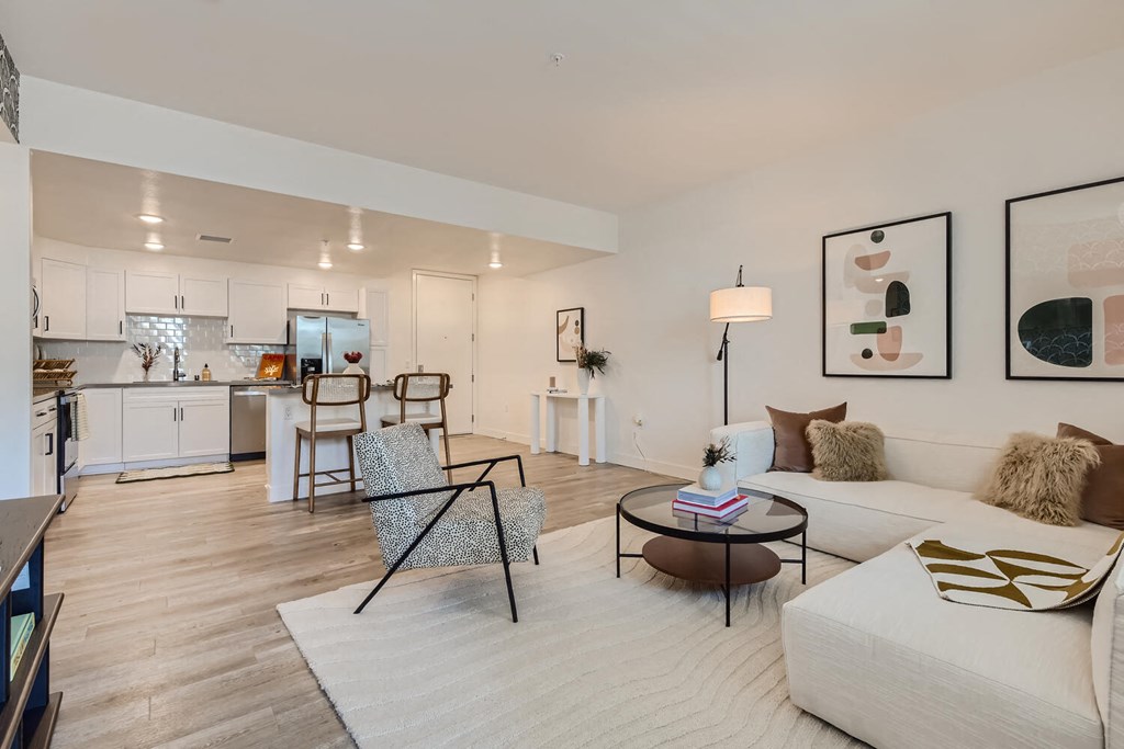 a living room with a white couch and two chairs at The Venue at Orange Apartments, Redlands, California