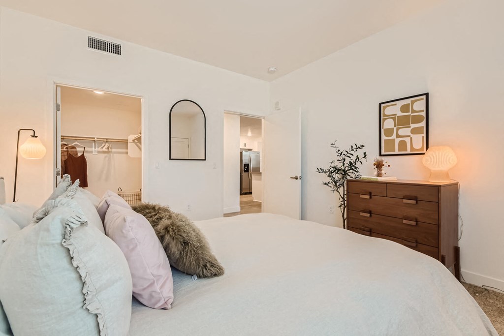 a bedroom with a large bed and a dresser with a mirror at The Venue at Orange Apartments, Redlands