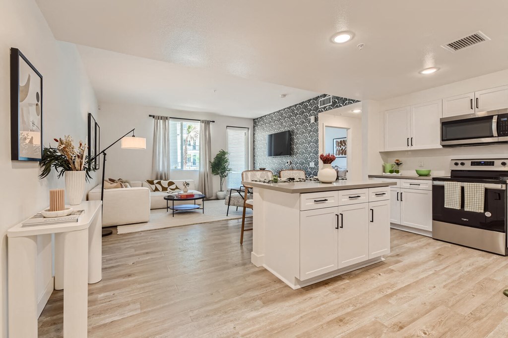 a kitchen and living room with white walls and wood flooring at The Venue at Orange Apartments, Redlands, CA, 92373