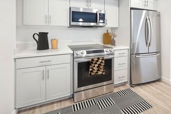 A modern kitchen with a stainless steel refrigerator, a microwave above the stove, and white cabinets.