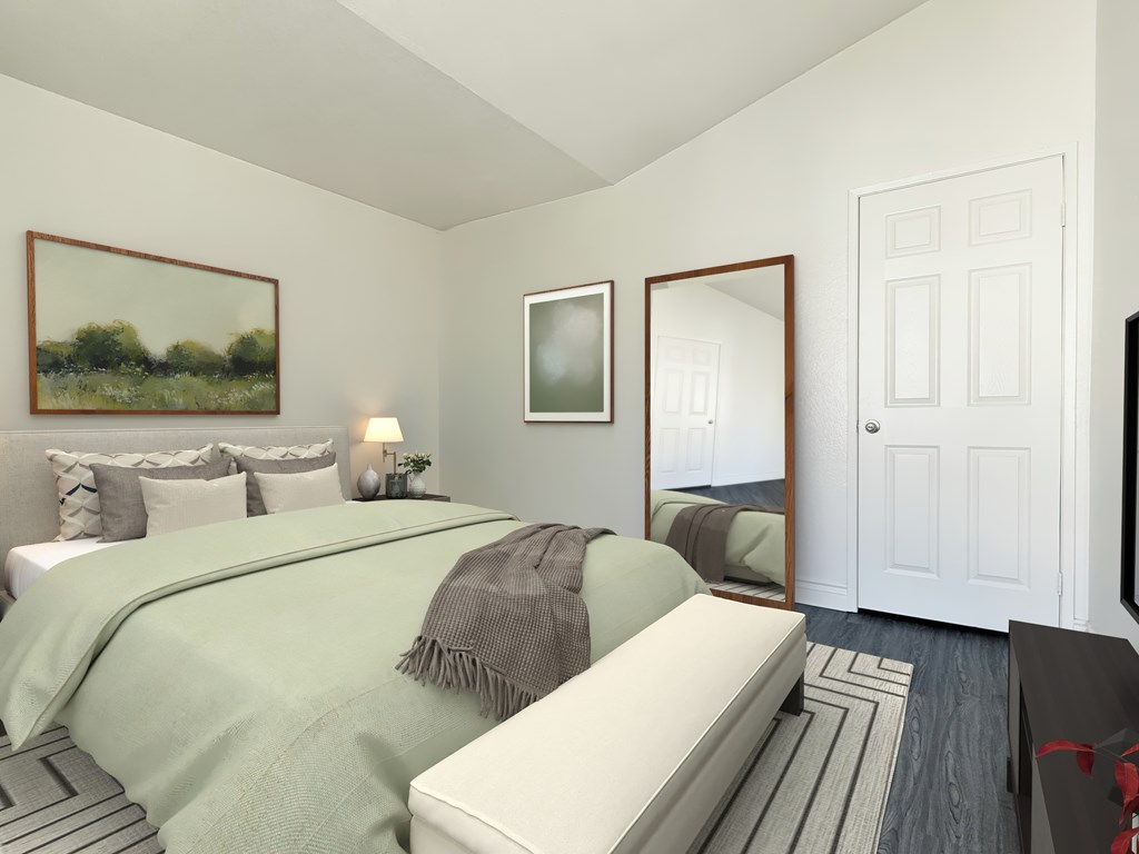 A bedroom with a bed, a mirror, and a painting on the wall at Ridgeline Apartments in San Bernardino
