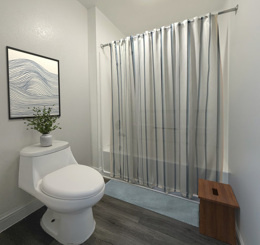 A bathroom with a white toilet and a shower curtain at Broadview Apartments, San Bernardino California