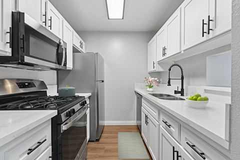 A modern kitchen with white cabinets and stainless steel appliances.