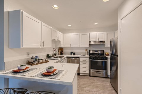 A modern kitchen with a dining table set for two.