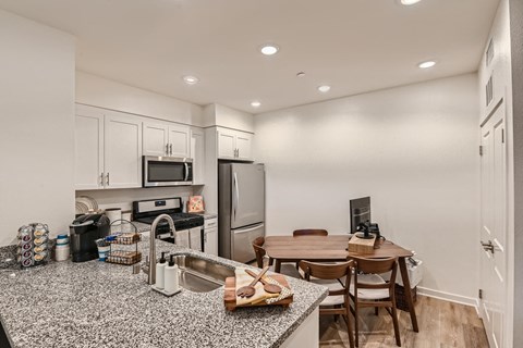 A kitchen with a granite countertop and a dining table with chairs.