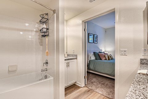 a bathroom with a shower and a bed in the background