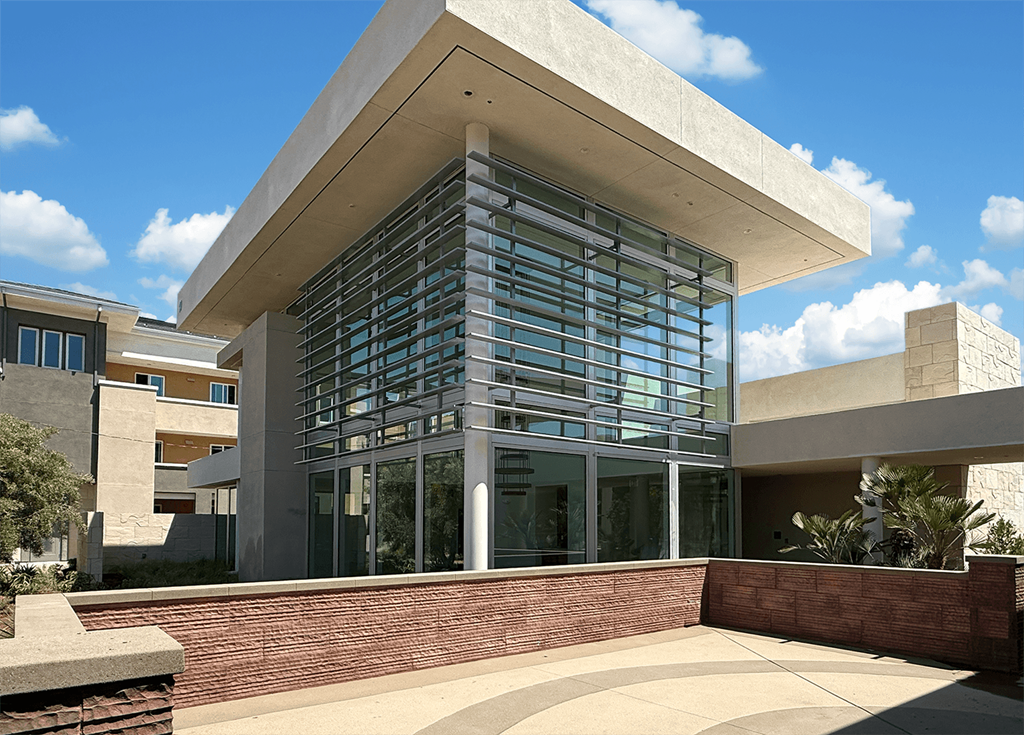 A modern building with a glass facade and a curved walkway in front.at The Park on Washington, Murrieta California