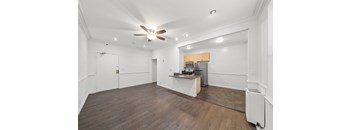 A room with a ceiling fan and a kitchenette.