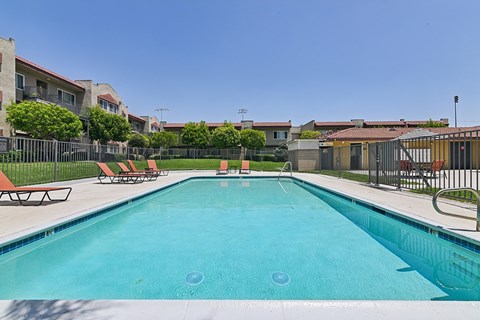 A swimming pool surrounded by a fence and chairs.