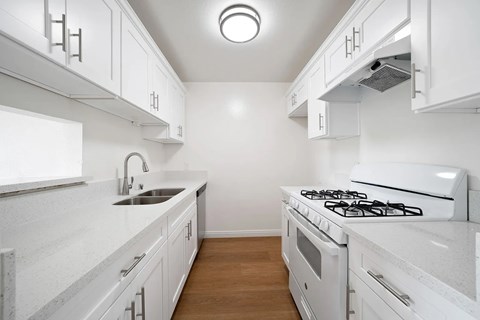 A white kitchen with a stove and sink.