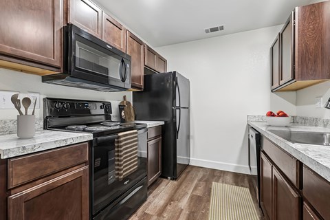 A kitchen with dark wood cabinets and black appliances.
