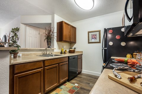 A kitchen with wooden cabinets and a black refrigerator.