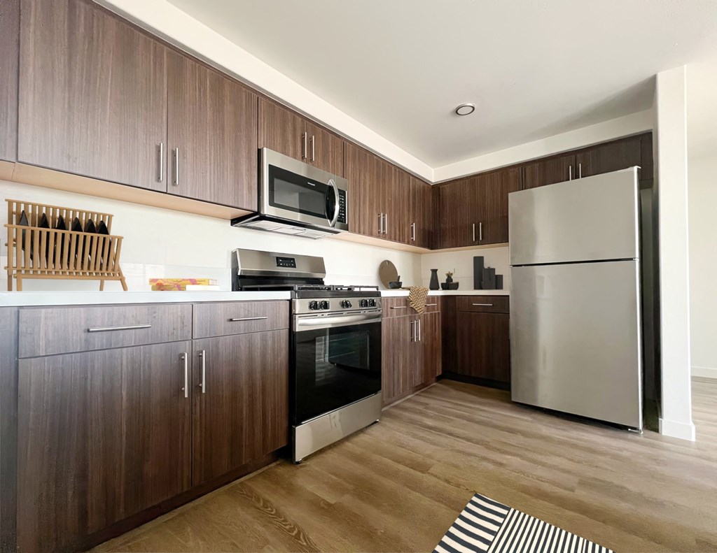 a kitchen with stainless steel appliances and wooden cabinets at The Max on Jefferson Apartments, California, 92562