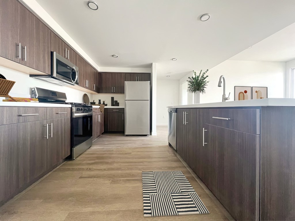 a kitchen with wooden cabinets and stainless steel appliances at The Max on Jefferson Apartments, Murrieta, California