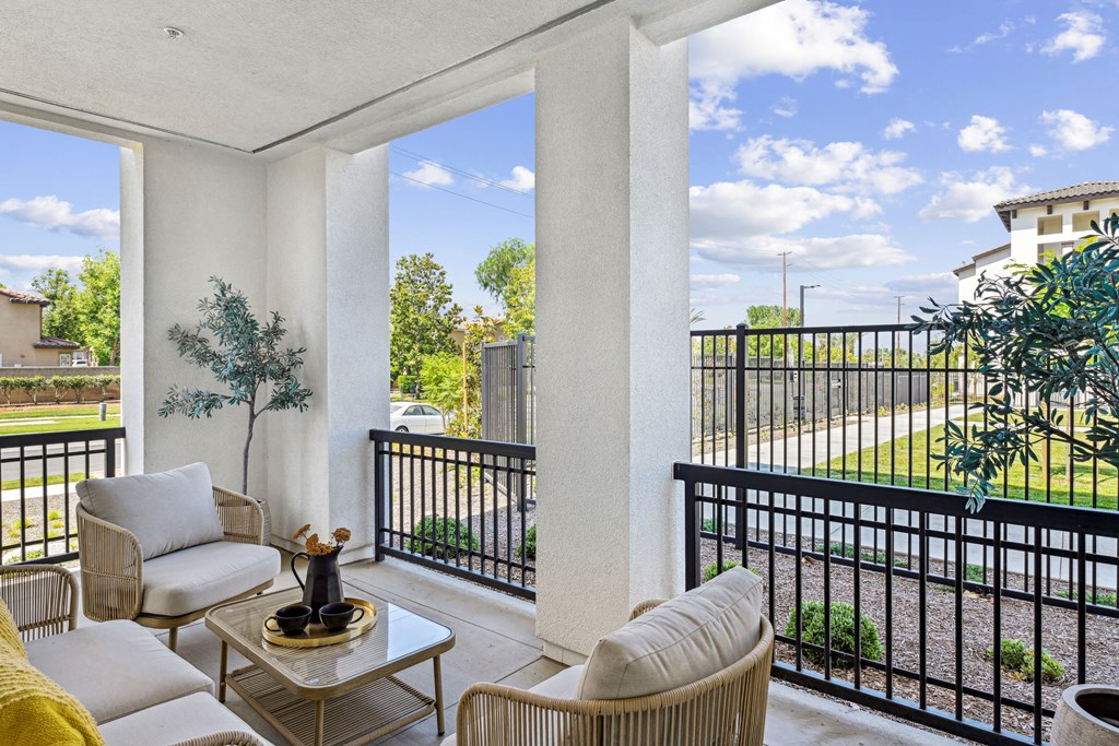 a living room with two couches and a table on a balcony at The Venue at Orange Apartments, Redlands, CA