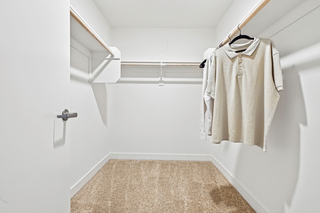 a spacious walk in closet with a white wall and a white closet door  at The Venue at Orange Apartments, California