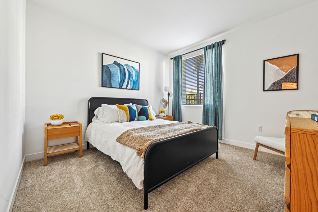 a bedroom with a bed and a dresser and a window at The Venue at Orange Apartments, Redlands, California