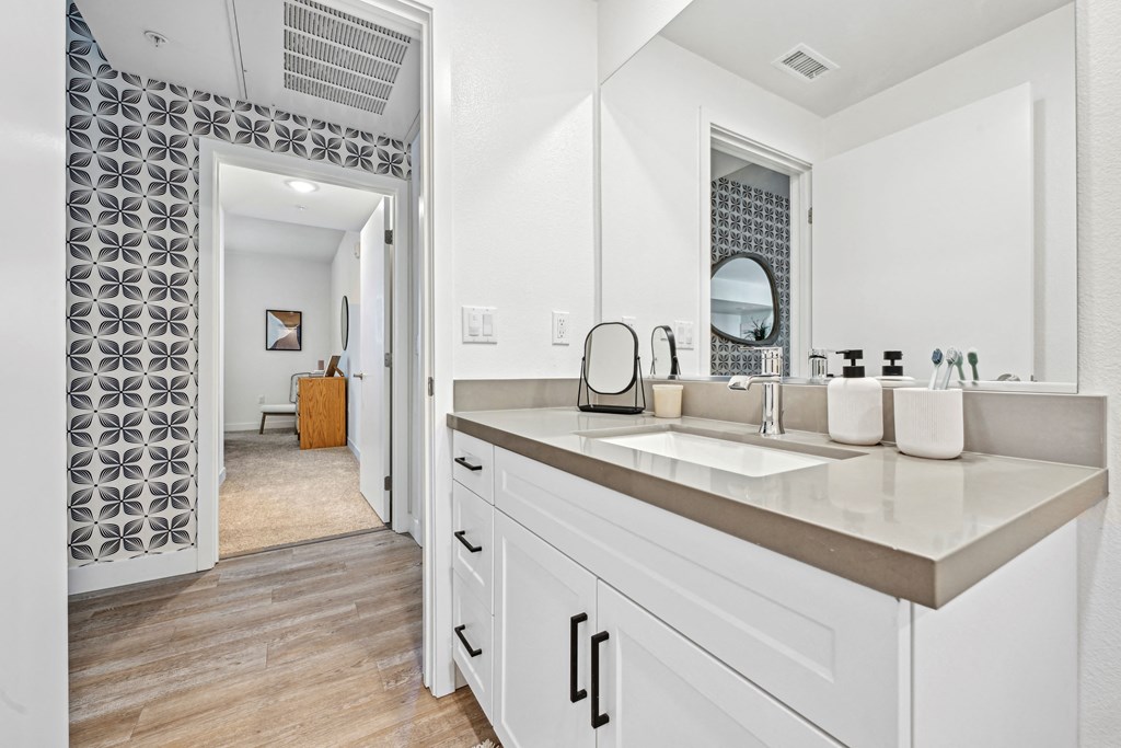 a large white bathroom with a sink and a mirror at The Venue at Orange Apartments, Redlands