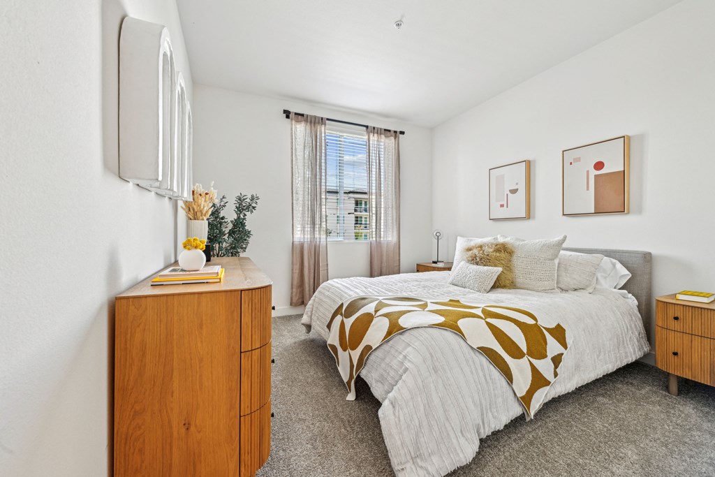 a bedroom with a bed and a dresser and a window at The Venue at Orange Apartments, Redlands, CA