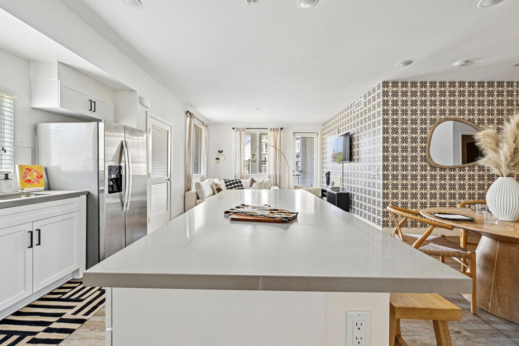 a kitchen with a white counter top and a stainless steel refrigerator at The Venue at Orange Apartments, Redlands, CA, 92373