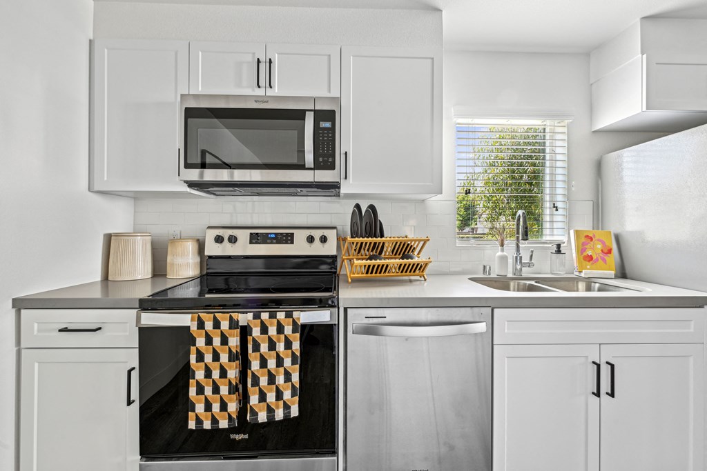 a modern kitchen with white cabinets and stainless steel appliances at The Venue at Orange Apartments, Redlands, California