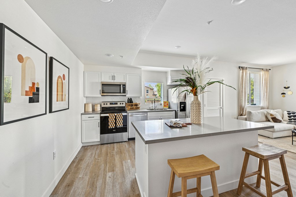 an open kitchen and living room with an island and stools at The Venue at Orange Apartments, California, 92373