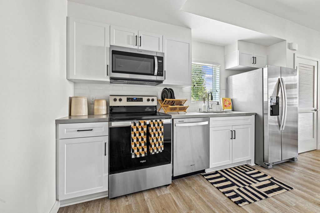 a kitchen with stainless steel appliances and white cabinetry at The Venue at Orange Apartments, Redlands, CA, 92373