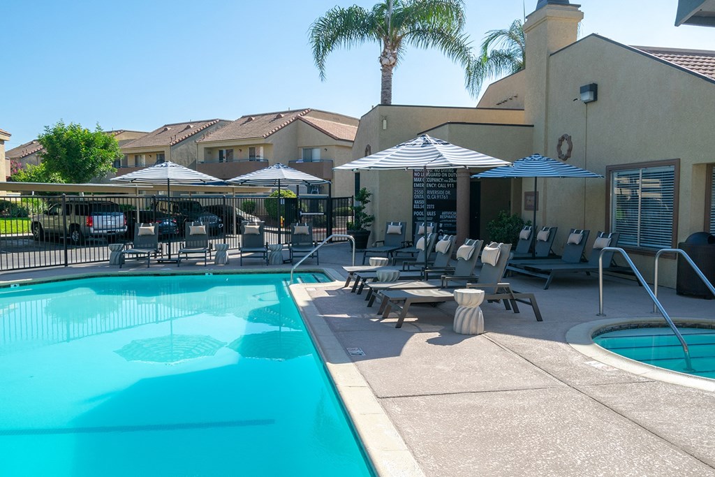 a swimming pool with tables and umbrellas in front of leasing office