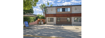 A two-story building with a garage door and a sign that says "For Rent".