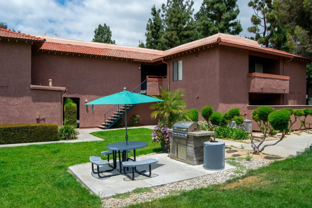 a patio with a table and umbrella in front of a building