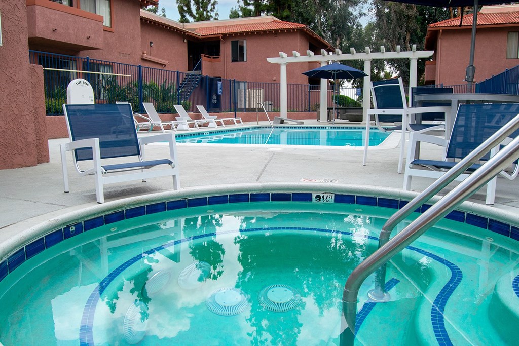 a swimming pool with a hot tub and lounge chairs in front of a building