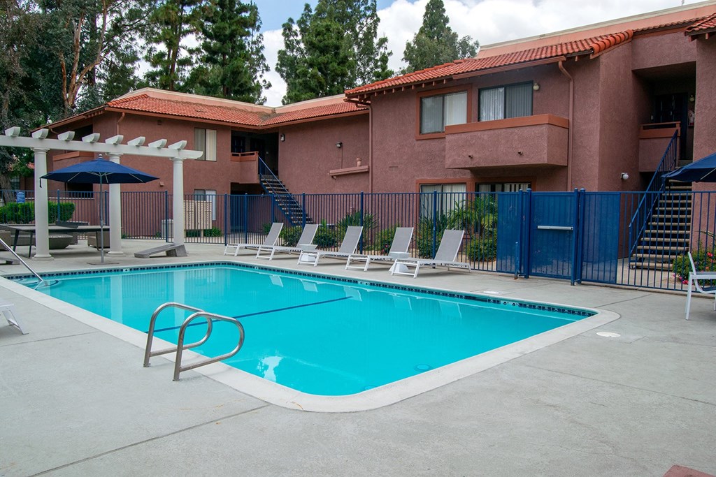 a swimming pool with chaise lounge chairs and umbrellas in front of a red brick