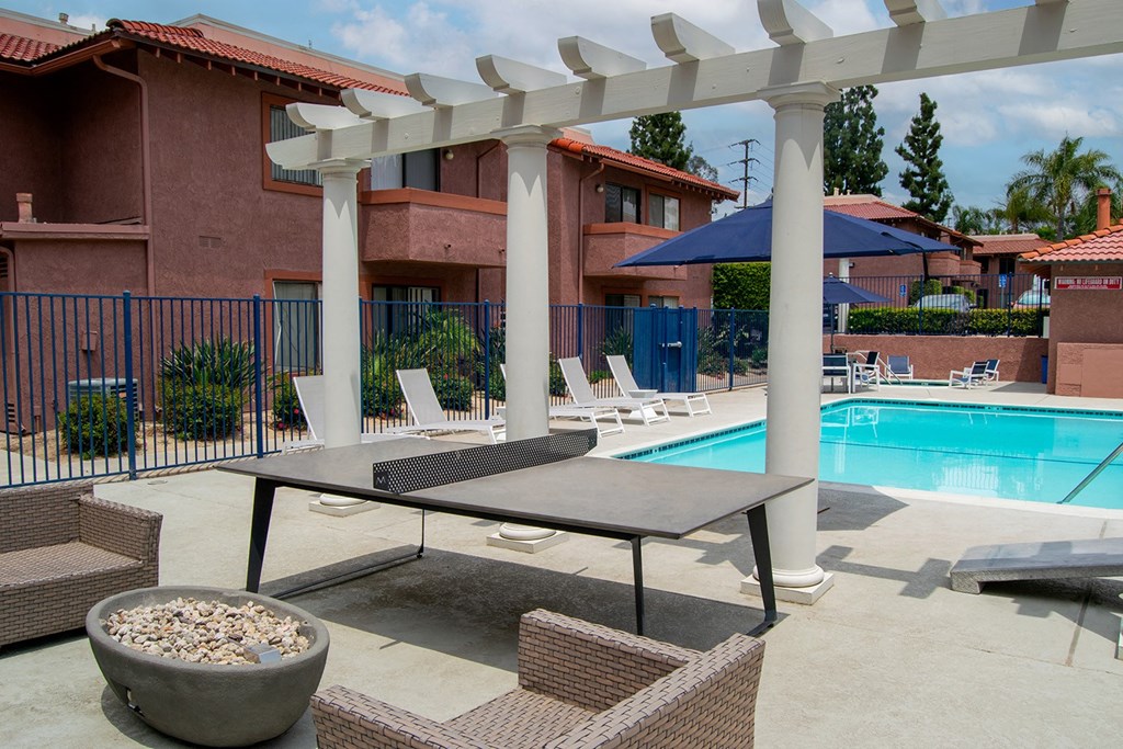 a patio with a table and chairs and a swimming pool in the background