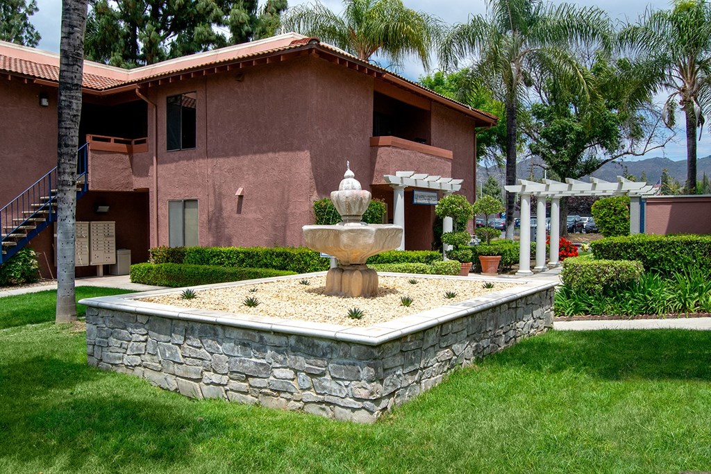 a fountain in the middle of a grassy area in front of a building