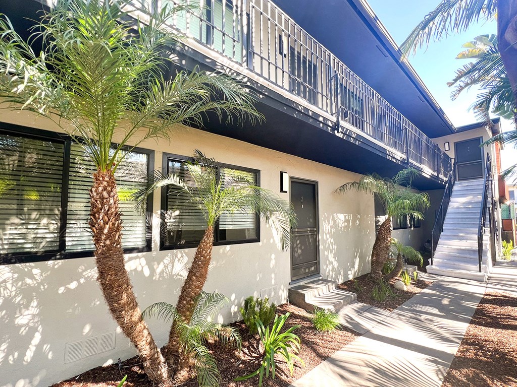 a house with a balcony and palm trees in front of it