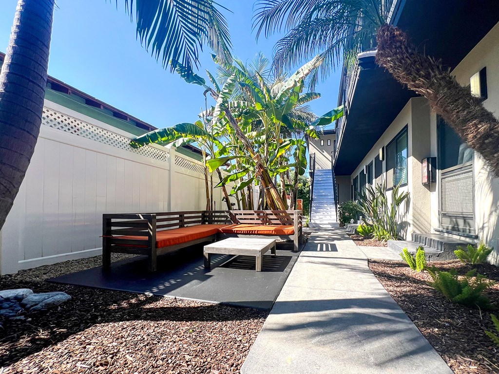 a courtyard with benches and palm trees in front of a building