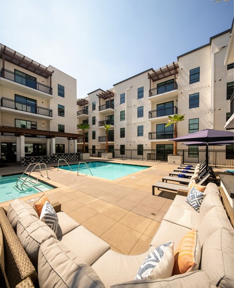 A pool area with a row of lounge chairs and a purple umbrella.