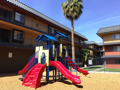 A playground with a red slide and a blue canopy.