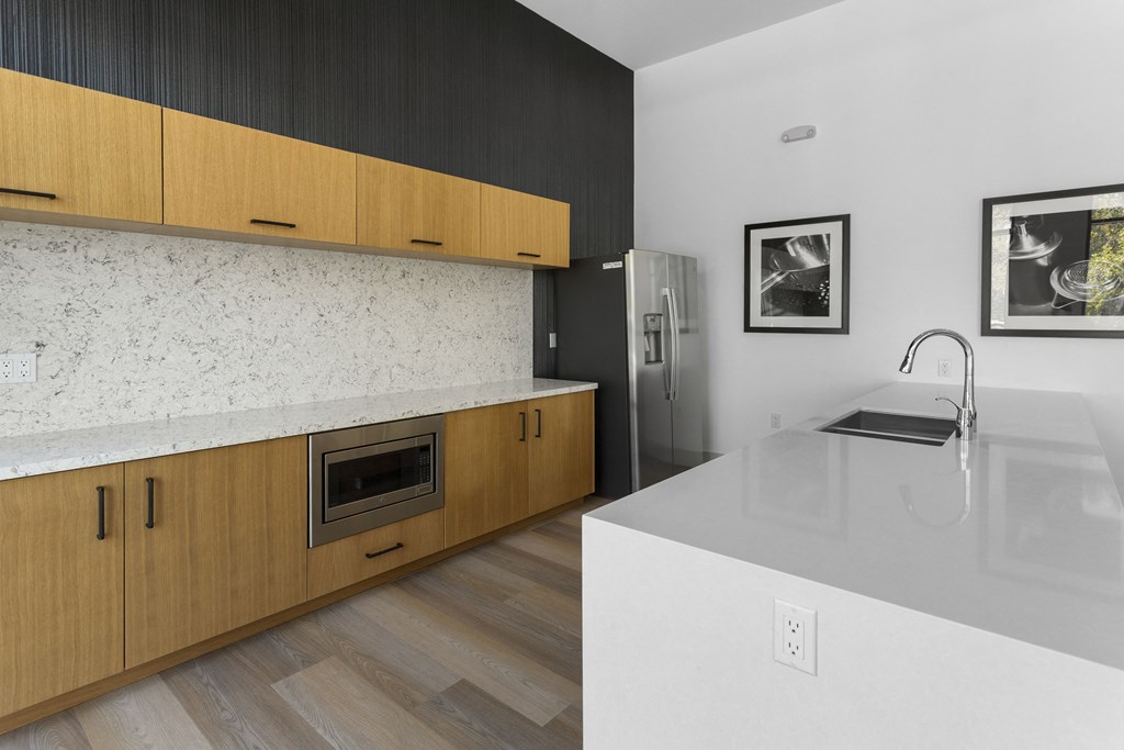 a kitchen with wooden cabinets and a white counter top and a sink at The Venue at Orange Apartments, Redlands, CA