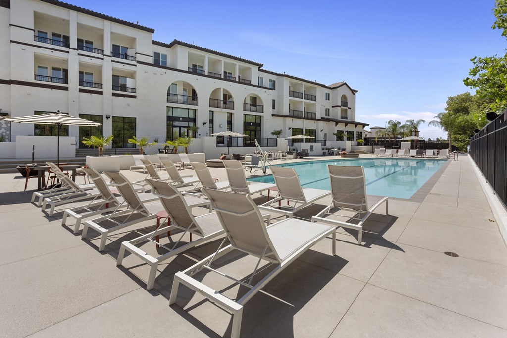 a large pool with lounge chairs in front of a building at The Venue at Orange Apartments, Redlands, 92373