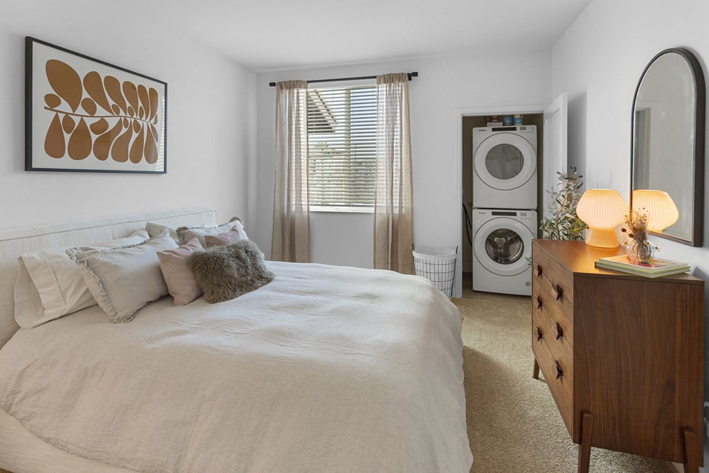 a bedroom with a bed and a washer and dryer at The Venue at Orange Apartments, Redlands, CA